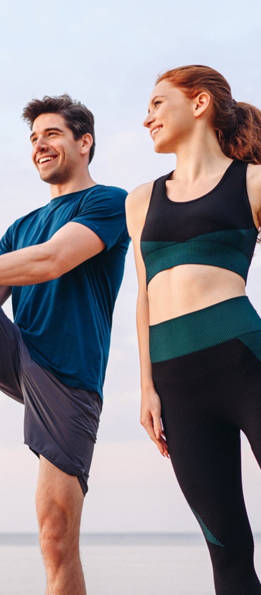 Lower couple young two friend strong sporty sportswoman sportsman woman man in sport clothes warm up training do stretch exercise on sand sea ocean beach outdoor jog on seaside in summer day morning