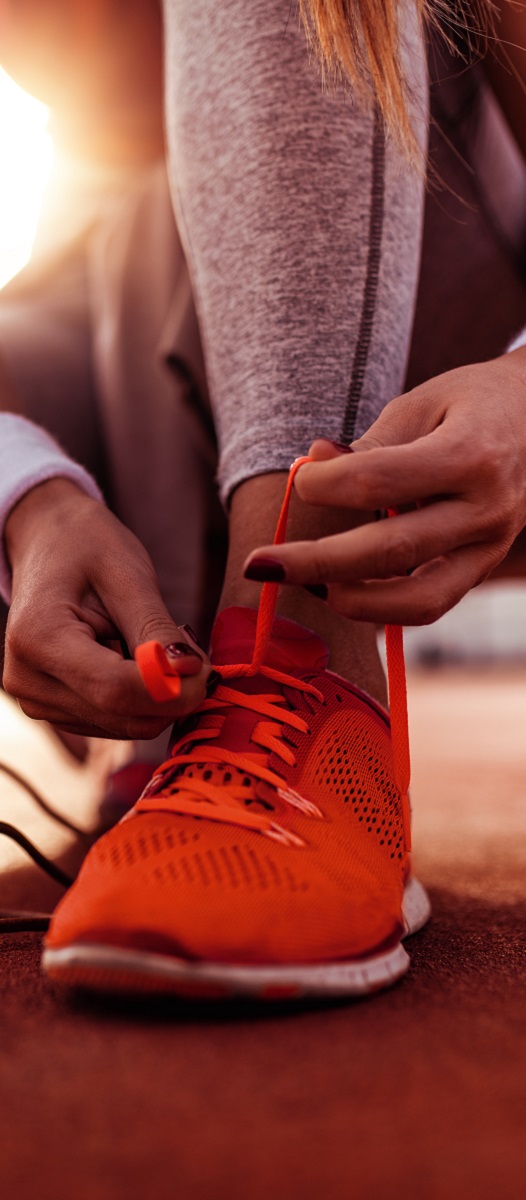 Female runner tying her shoes and preparing for a jogging.